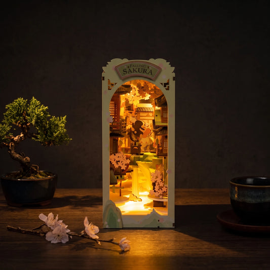 Book Nook Falling Sakura en ambiance nocturne, lueur LED ambre chaude, décor japonisant zen avec bonsaï et tasse à thé
