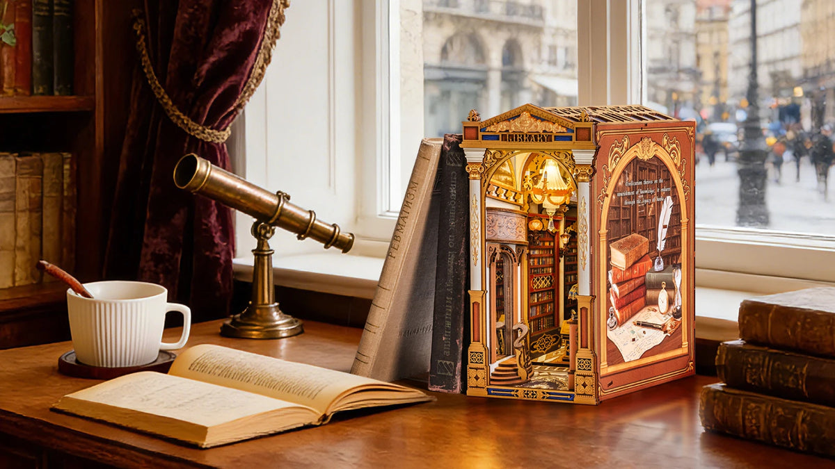 Book nook Library of Wonders sur un bureau près d'une longue-vue et d'une fenêtre