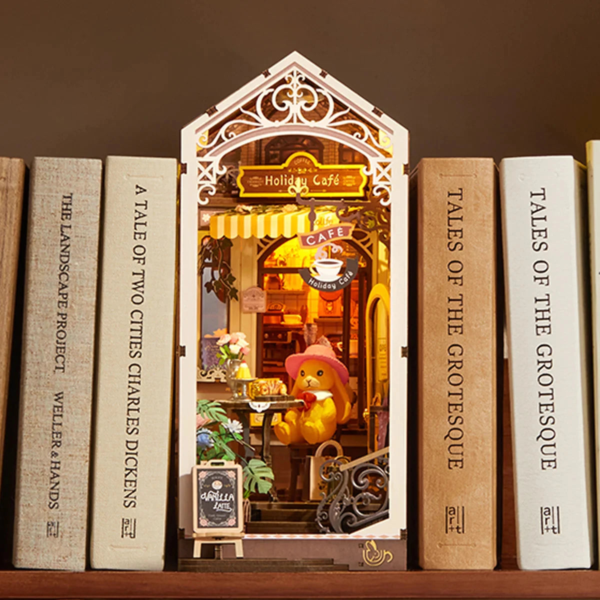 Book nook Holiday Café glissé entre des livres sur une étagère
