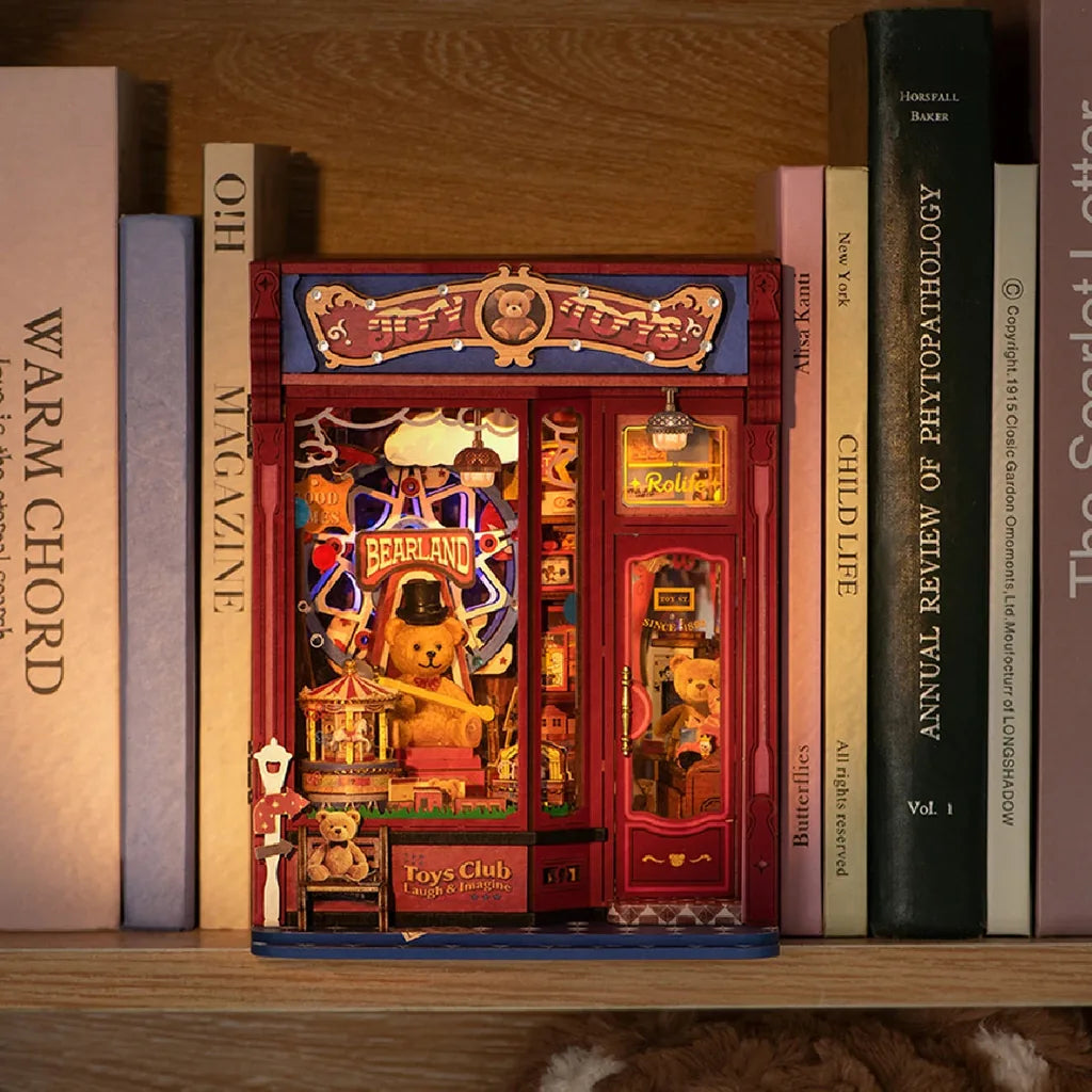 Book nook Joy Toys allumé entre des livres sur une étagère en soirée