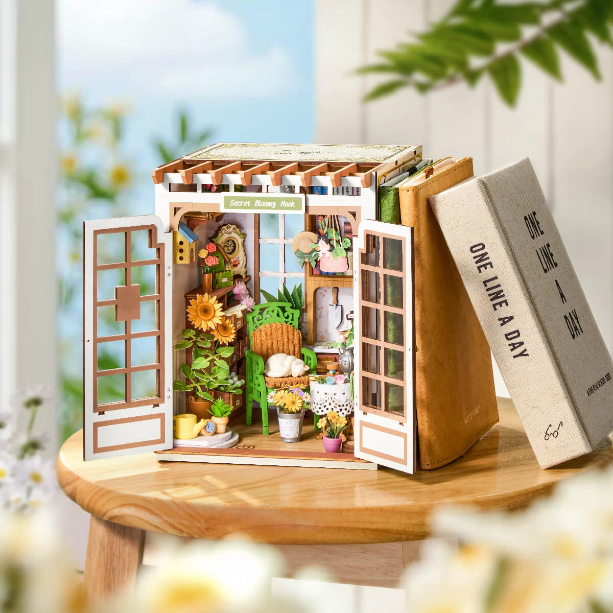 Book nook Secret Bloomy Nook au soleil sur un tabouret, entre deux livres