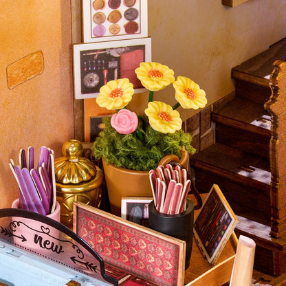 Détail du book nook papeterie avec pot de fleurs jaunes et crayons colorés