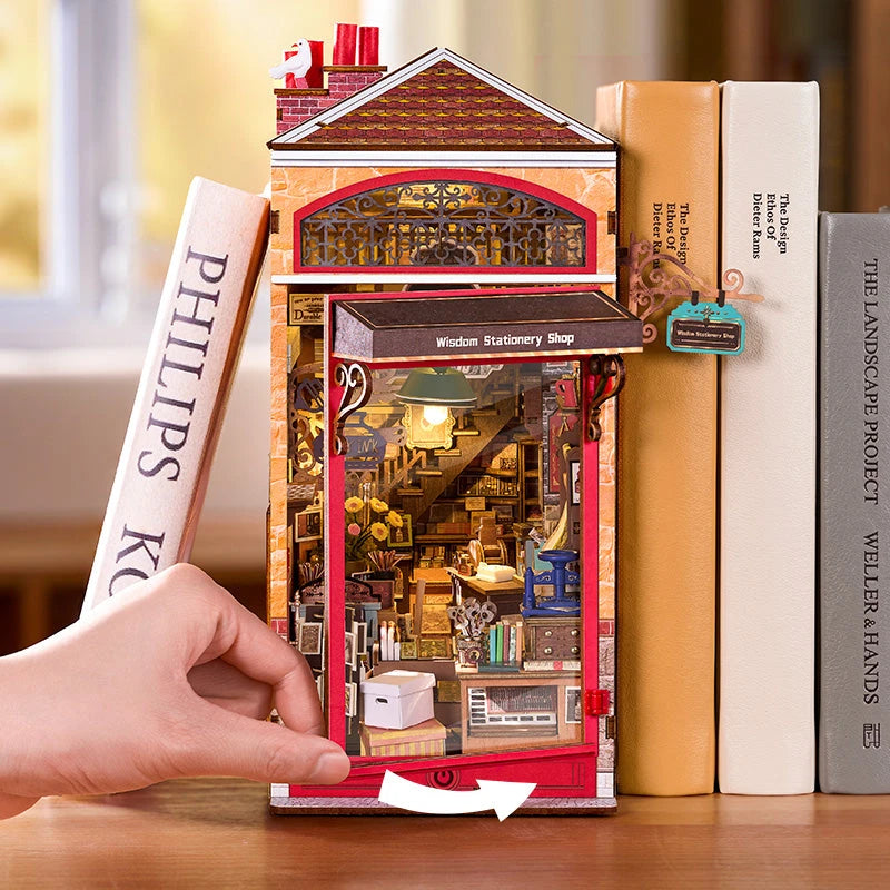 Main ouvrant la vitrine anti-poussière rouge du book nook Wisdom Stationery Shop