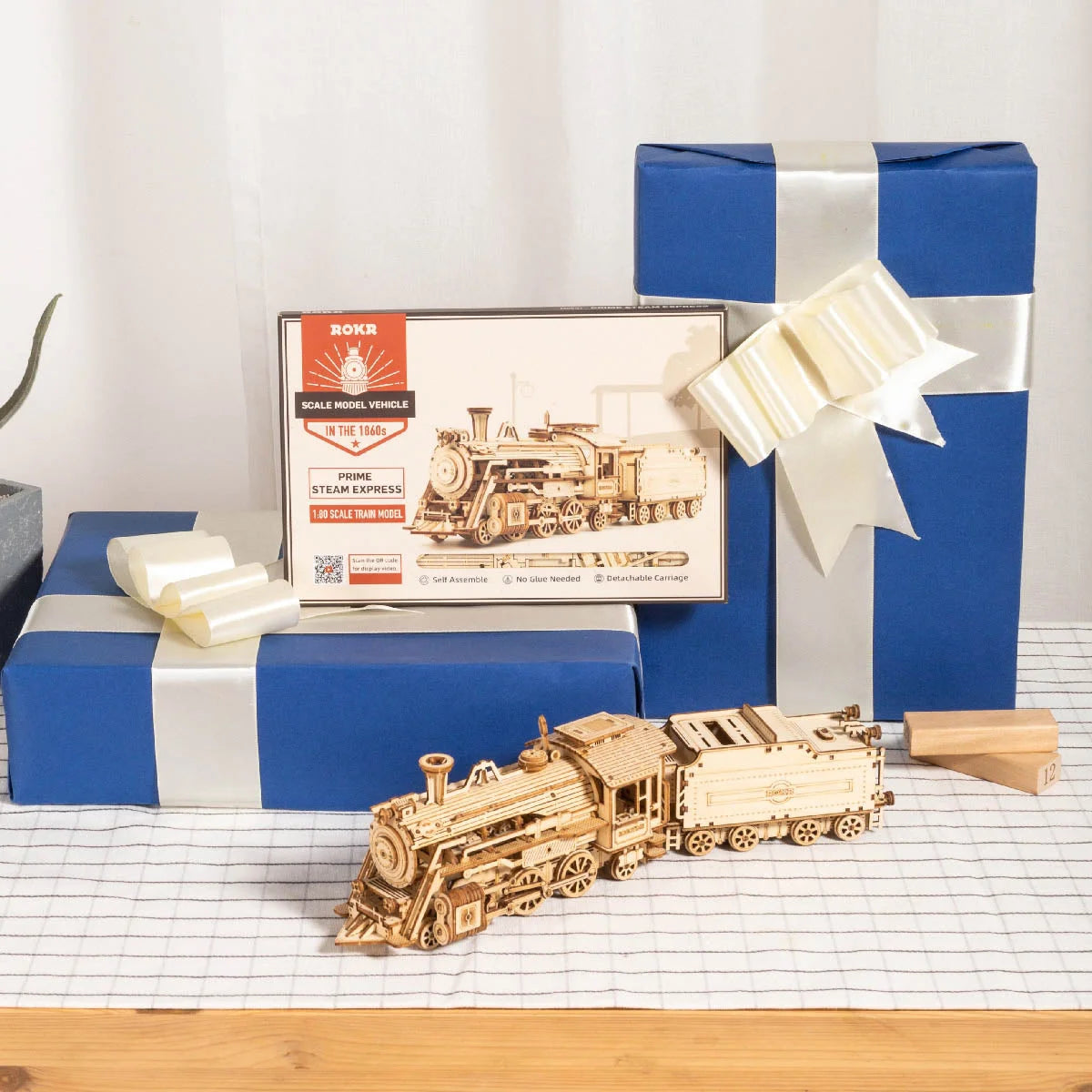 Locomotive à vapeur en bois devant sa boîte ROKR et des paquets cadeaux