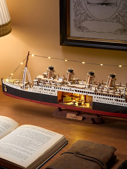 Maquette Titanic 1912 éclairée la nuit près d'une lampe et d'un livre ancien ouvert