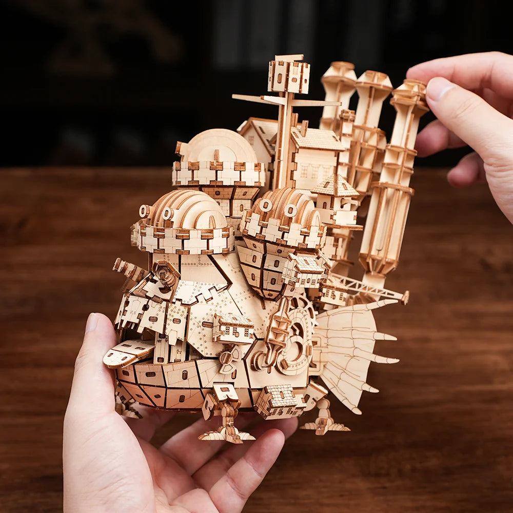 Château Ambulant en bois naturel tenu à deux mains, pour donner l'échelle du puzzle