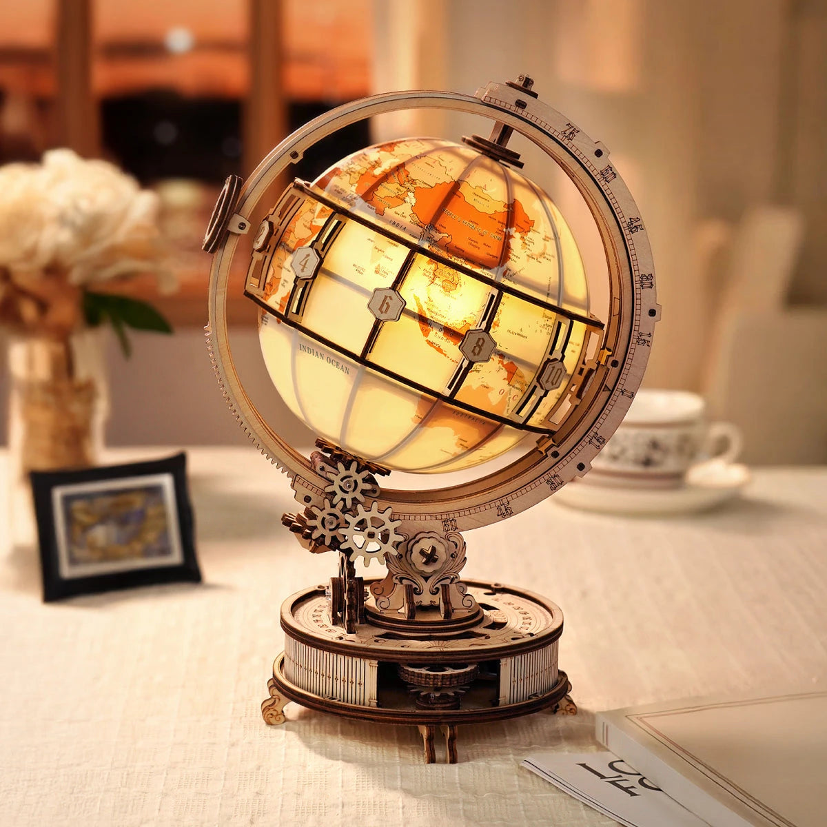 Globe lumineux en bois allumé dans un salon, bouquet de fleurs et cadre