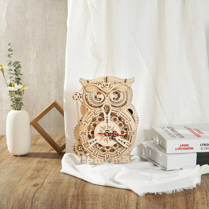 Horloge hibou en bois sur un bureau clair avec livres et lin blanc