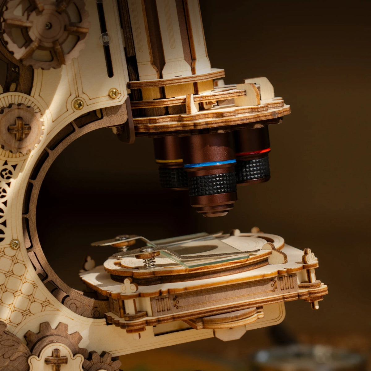 Gros plan sur les trois objectifs cuivrés et la platine du microscope vintage en bois