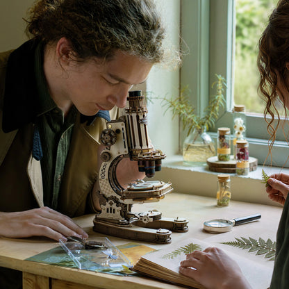 Observation de spécimens végétaux avec le microscope vintage puzzle 3D près d'une fenêtre