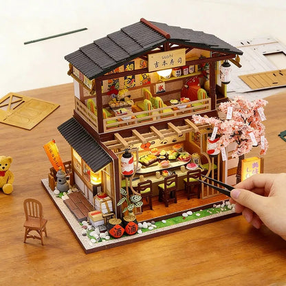 Restaurant Gibbon Sushi miniature en bois, main disposant des baguettes pour montrer l'echelle du diorama