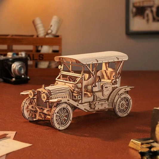 Le Roadster Rétro en bois posé sur un bureau éclairé, plan large avec appareil photo et objets anciens