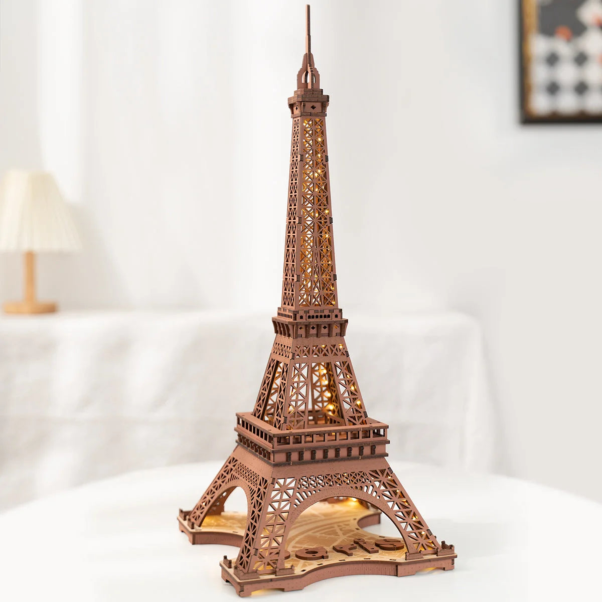 Tour Eiffel en bois non éclairée posée sur une table blanche, vue de biais